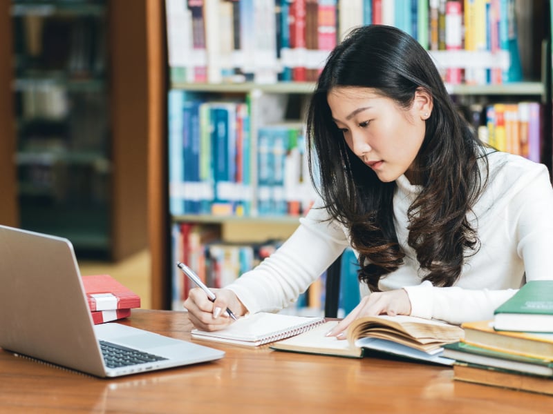 young woman studying at the library